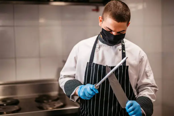 Chef sharpening knife in restaurant kitchen.