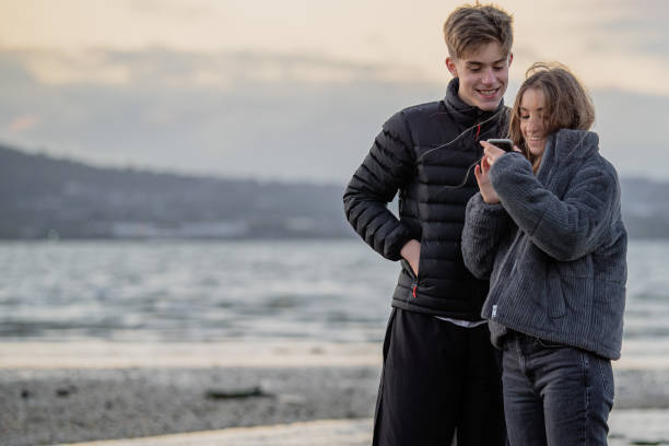 adolescentes em uma praia olhando para um celular - telephone nature mobile phone autumn - fotografias e filmes do acervo