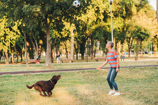 Mid adult woman enjoying playing with her dog in the park.