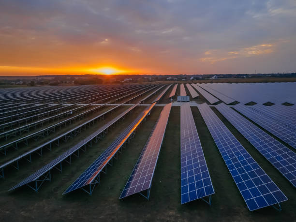 istock Aerial drone view into large solar panels at a solar farm at bright sunset. Solar cell power plants. 1281713279