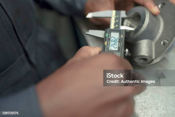 Hands Detail Of Black Man Worker Measuring Machinery Part With Digital Caliper At Factory Stock Photo - Download Image Now