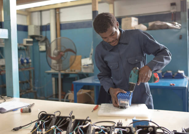 istock Black man worker using electric screwdriver on device at factory 1281720187
