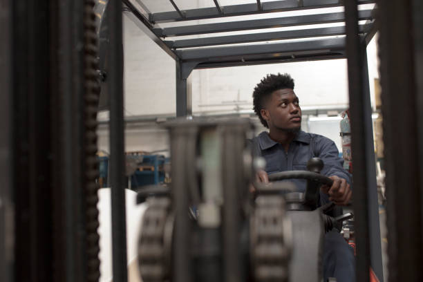 istock Young black man employee working in a forklift at a factory. 1281720207