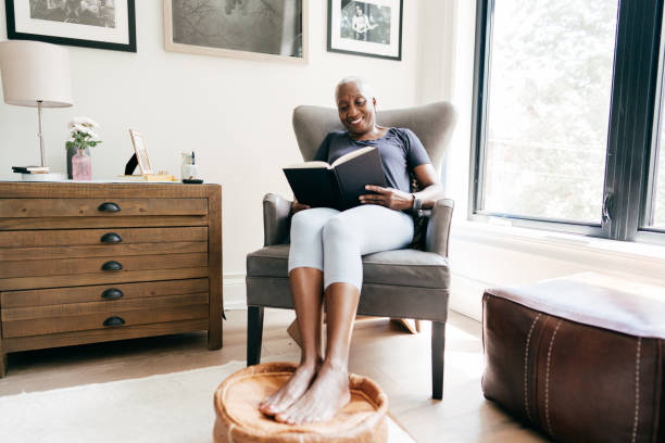 家で本を読む70歳の格好良い先輩女性 - old armchair women senior adult ストックフォトと画像