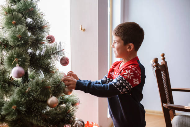 istock Little boy decorating Christmas tree at home. 1281725552