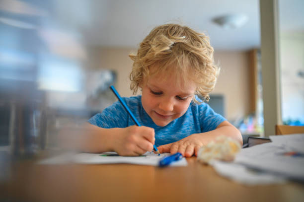 istock Young blond boy coloring books at home 1281729366