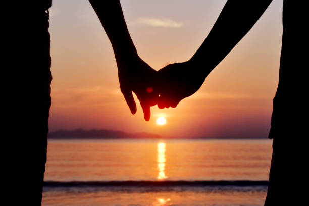 istock Lovers' hand holding each other with sunset at sea 1281732373