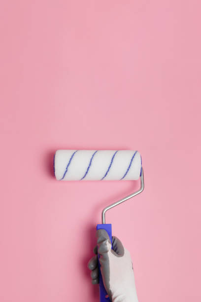 istock Paint roller in gloved hand on pink background 1281741132