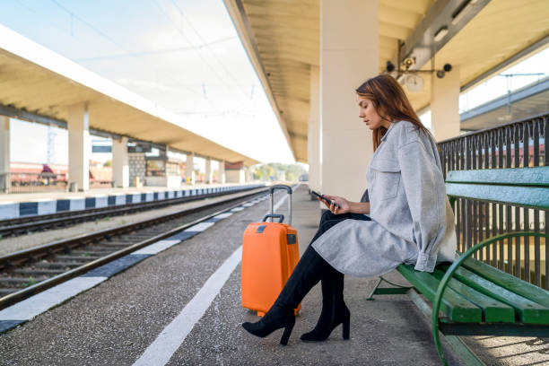 istock Young woman waiting on station and using smart phone 1281744630