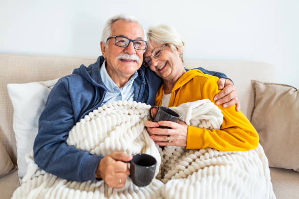 istock Happy old couple sitting on the sofa. Feeling cozy,drinking coffee or tea 1281745569