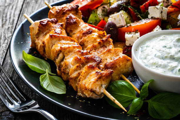 スブラキ - 木製のテーブルの上に焼き肉、ギリシャのサラダとツァツィキ - greek cuisine chicken grilled grilled chicken ストックフォトと画像