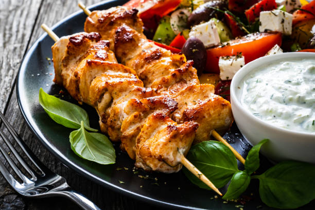 souvlaki - grilled meat, greek salad and tzatziki on wooden table - souvlaki imagens e fotografias de stock