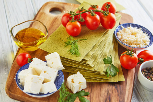istock Sheets for making lasagna with spinach and ingredients: cherry tomatoes, cheese, butter, peppers and herbs 1281754265