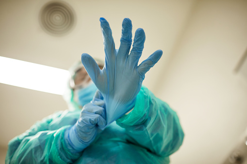 Trabajador sanitario masculino poniéndose guantes quirúrgicos photo