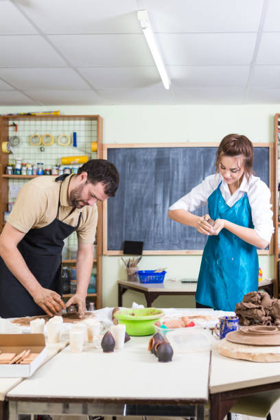 istock Pottering Process Concept. Two Professional Ceramists or Claymakers During a Process of Clay Preparation on Tables in Workshop. Vertical Image 1281757215