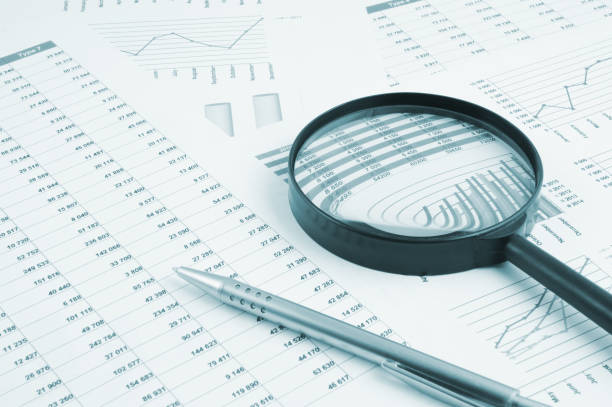 istock Magnifying glass and pen on financial charts and graphs 1281758129