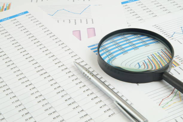 istock Magnifying glass and pen on financial charts and graphs 1281758146