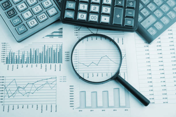 istock Calculators and magnifying glass on financial charts and graphs 1281758285