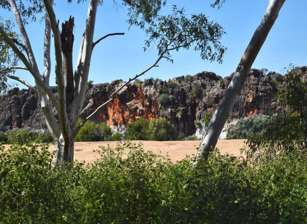 Geikie Gorges are located North of Fitzroy Crossing (Kimbely Region/Australia/WA). It is a National Park. On this photo it is possible to see a dry part of the Fitzroy River.  It is also possible to see the impressive orange and grey cliff.