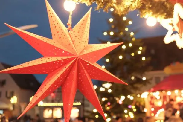 Christmas and New Year in Europe.Winter Christmas Holidays. Christmas Festive Street Decor Christmas Paper Stars Lanterns in the Holiday Market.street decor on festive christmas town background.