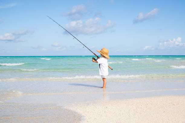 Young boy stands in the shallow sea, gripping a long blue pole with a fishing net at the end. His expression tells the story: eyes fixed on the empty net, a quiet realization settling in. He truly believed he could catch fish, only to face the harsh truth of reality. Fishing in the sea is far more difficult than he imagined. The warm glow of the setting sun contrasts with his quiet disappointment. The innocent optimism meets a world that does not bend to it.\nShot with Nikon D800