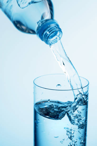 istock Pouring water from a bottle into glass on a blue background. 1281761894