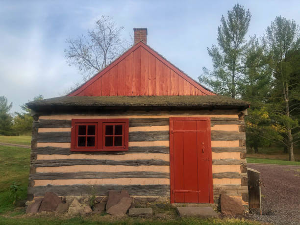 Colonial American log cabin with red door and window in natural setting