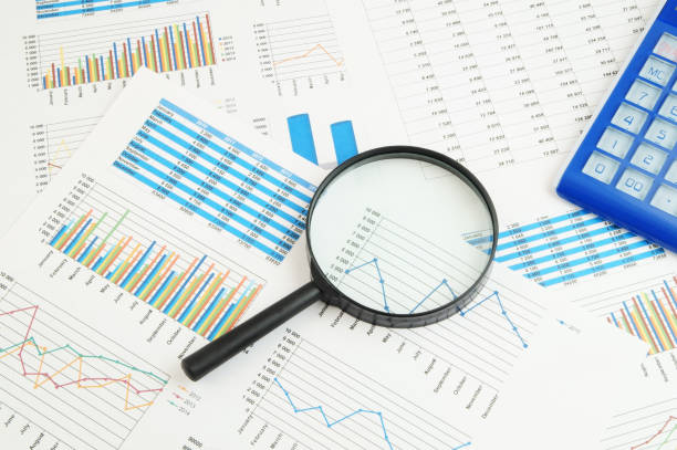 istock Calculator and magnifying glass on financial charts and graphs 1281763942