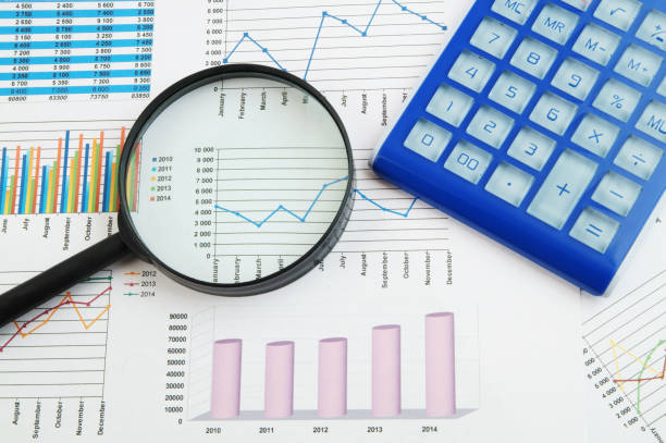 istock Calculator and magnifying glass on financial charts and graphs 1281763988
