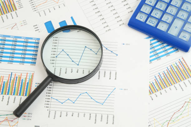 istock Calculator and magnifying glass on financial charts and graphs 1281763990