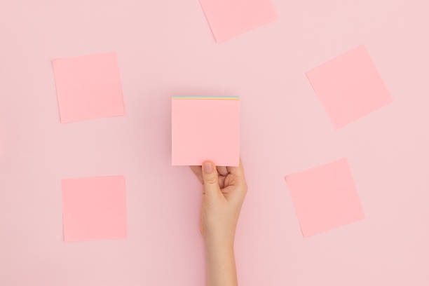 istock Woman's hand with glues pink sticker on a light pink background. 1281764159