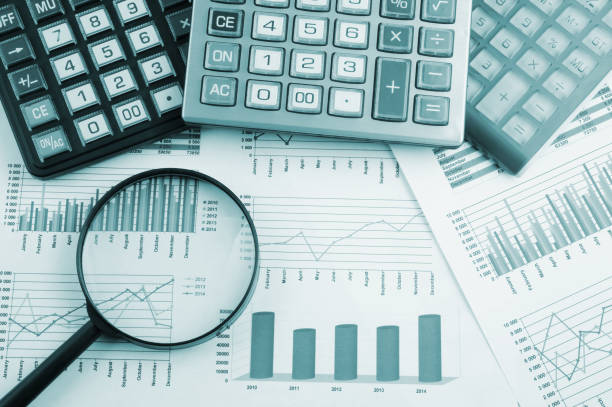 istock Calculators and magnifying glass on financial charts and graphs 1281764180