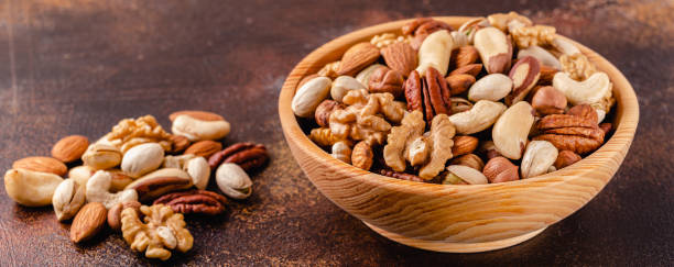 istock Various Nuts in wooden bowl on dark background 1281764385