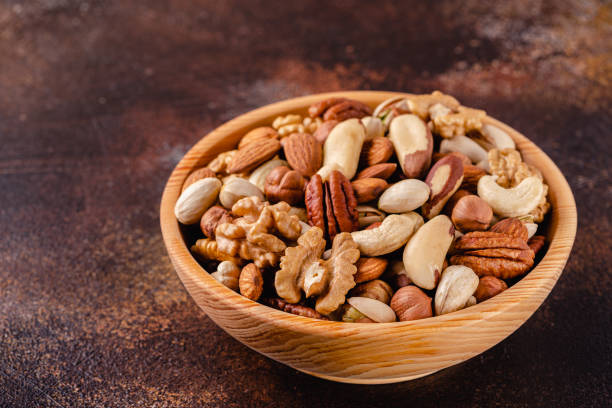 istock Various Nuts in wooden bowl on dark background 1281764392