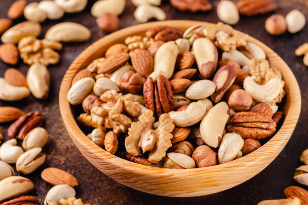 istock Various Nuts in wooden bowl on dark background 1281765038