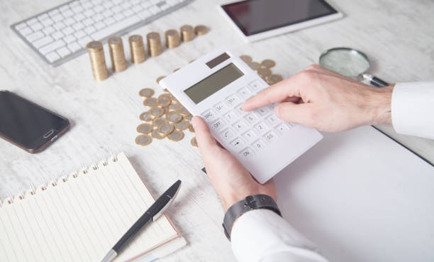 istock Businessman using calculator with coins on the desk. 1281766410