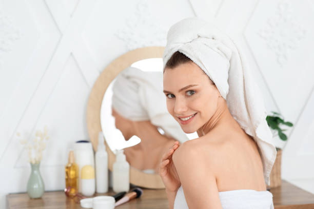 istock Happy lady wrapped in towel using body cream 1281767923