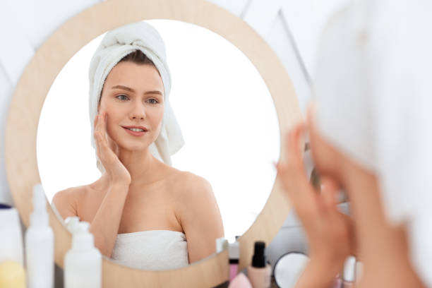 istock Cheerful young woman applying face cream, home interior 1281767939