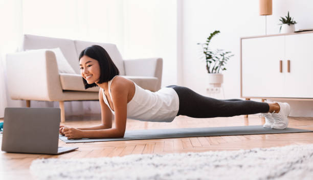 istock Sporty asian woman doing plank watching tutorial on laptop 1281768003