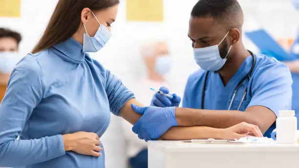 Photo of Doctor Injecting To Pregnant Woman Covid-19 Medicine Injection In Clinic