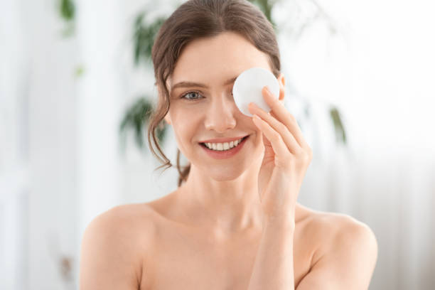 joven alegre quitando el maquillaje de sus ojos - hygienic pad fotografías e imágenes de stock