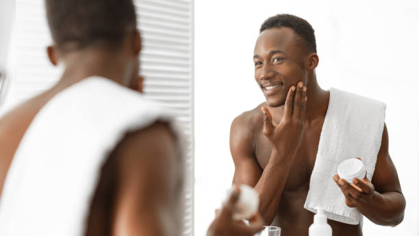istock Black Guy Using Facial Moisturizer Cream Standing Shirtless In Bathroom 1281768327