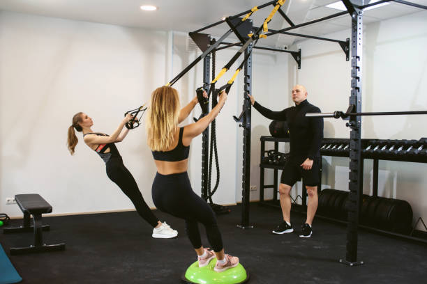 istock Two young female friends doing a cross training suspension workout with their trainer at a sports club. Private training with a personal coach. The concept of losing weight and gaining muscle mass. 1281770016