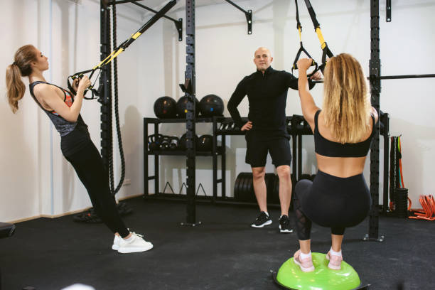 istock Two young female friends doing a cross training suspension workout with their trainer at a sports club. Private training with a personal coach. The concept of losing weight and gaining muscle mass. 1281770155