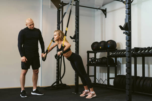 istock Private workout. Young woman doing push-ups gym suspension training with her personal trainer or coach in a fitness club. The concept of weight loss and gaining muscle mass. 1281771178