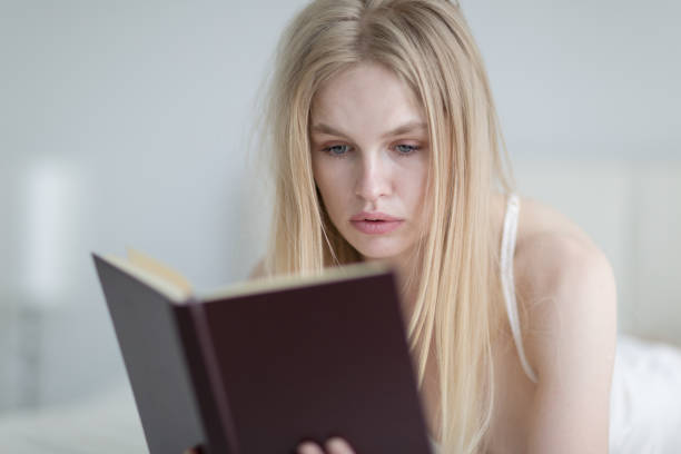 istock Young woman reading book in bed. 1281771233