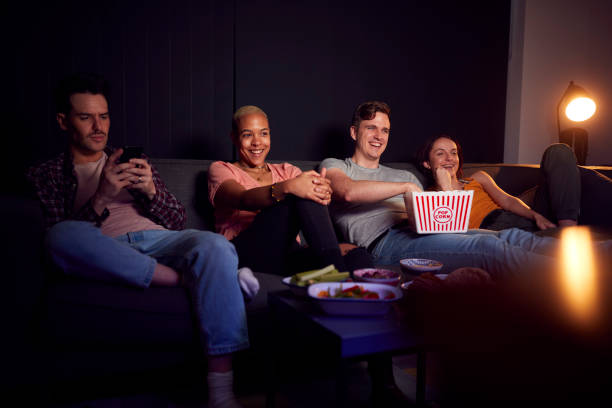 istock Man Using Mobile Phone Whilst Friends Watch TV At Home In Evening 1281771459