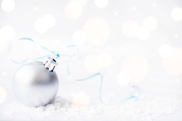 istock Christmas silver ball with ribbon on surface with snow and defocused lights with copy space 1281772196