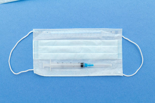 istock medical protective mask, syringe with copy space on a blue background. 1281774076