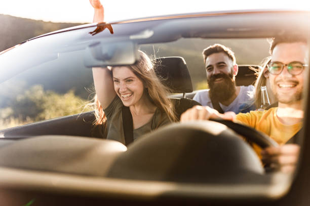 istock Young happy friends enjoying while going on their vacation by convertible car. 1281775212